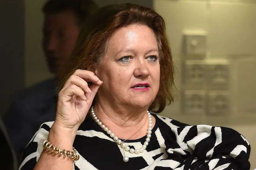 A woman wearing a black and white dress and pearls in conversation.