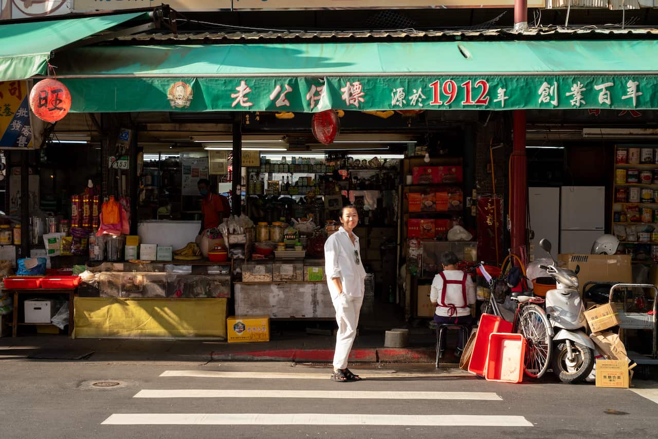 一位女士站在一家色彩鲜艳的店面前的行人过街处。
